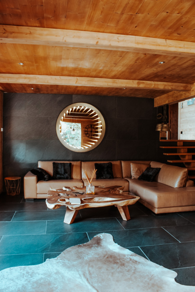 Cette image montre un très grand salon blanc et bois chalet en bois ouvert avec un mur noir, un sol en ardoise, une cheminée double-face, un manteau de cheminée en bois, un téléviseur indépendant, un sol noir, un plafond en bois et éclairage.
