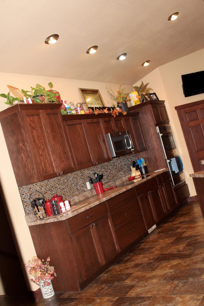 Example of a large transitional single-wall slate floor and beige floor enclosed kitchen design with shaker cabinets, dark wood cabinets, limestone countertops, beige backsplash, mosaic tile backsplash, stainless steel appliances and no island