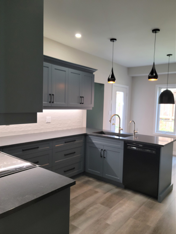 Inspiration for a mid-sized transitional u-shaped vinyl floor eat-in kitchen remodel with an undermount sink, recessed-panel cabinets, blue cabinets, quartzite countertops, white backsplash, porcelain backsplash, black appliances, a peninsula and black countertops