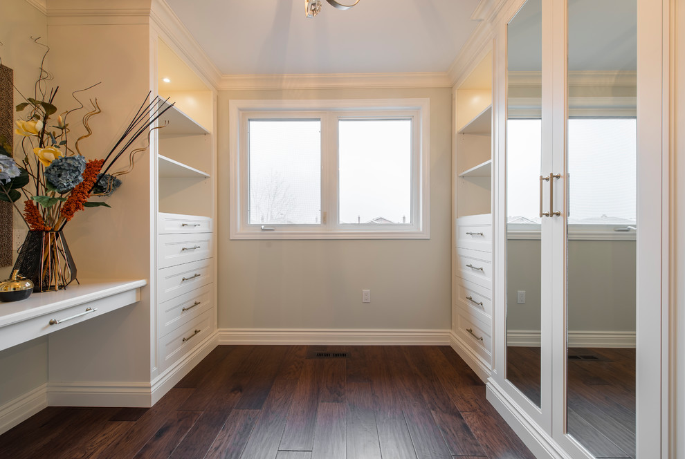 Large transitional gender-neutral walk-in wardrobe in Toronto with recessed-panel cabinets, white cabinets, dark hardwood floors and brown floor.
