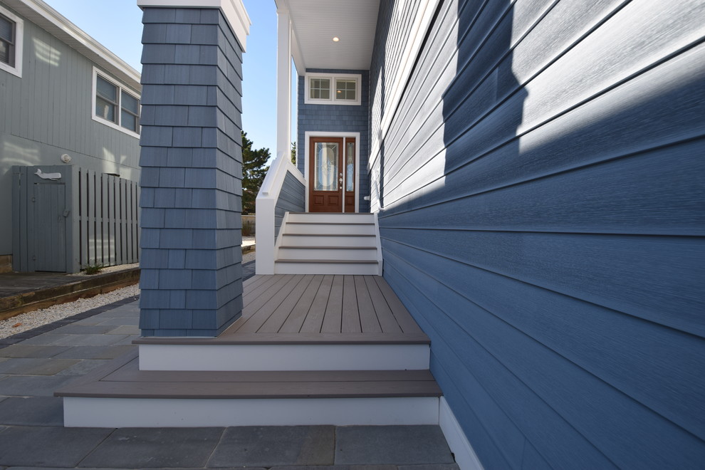 This is an example of a large beach style three-storey blue house exterior in Philadelphia with wood siding, a hip roof and a shingle roof.