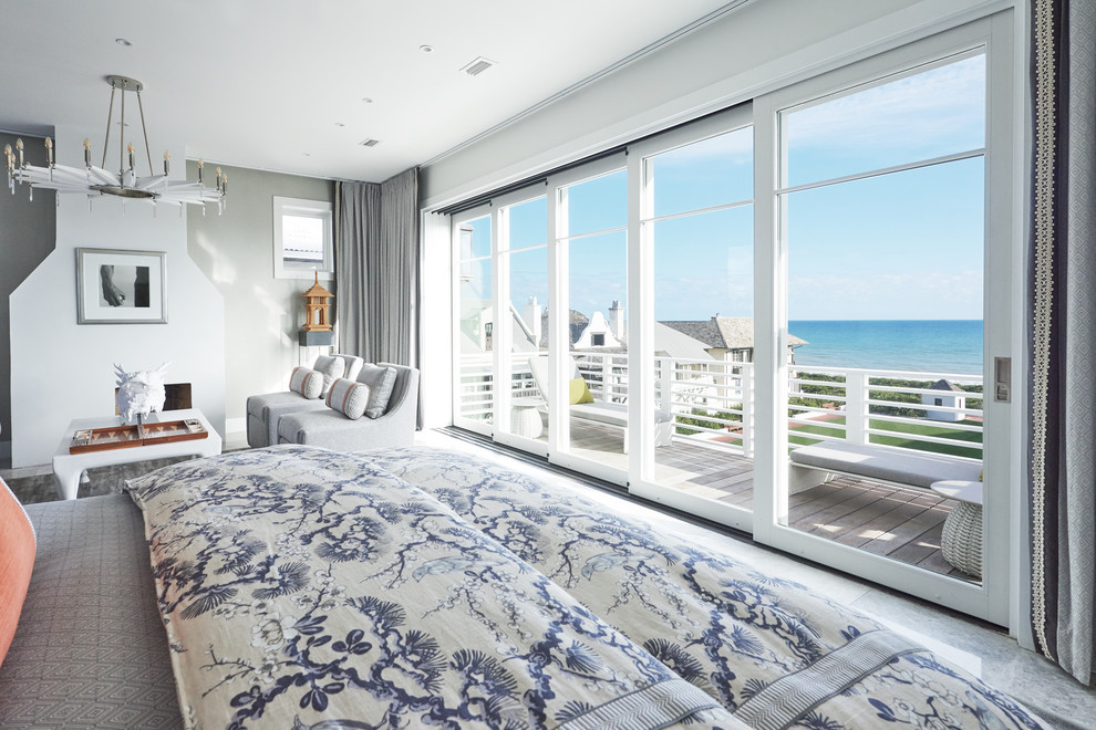 Design ideas for a large beach style master bedroom in Miami with grey walls and a standard fireplace.