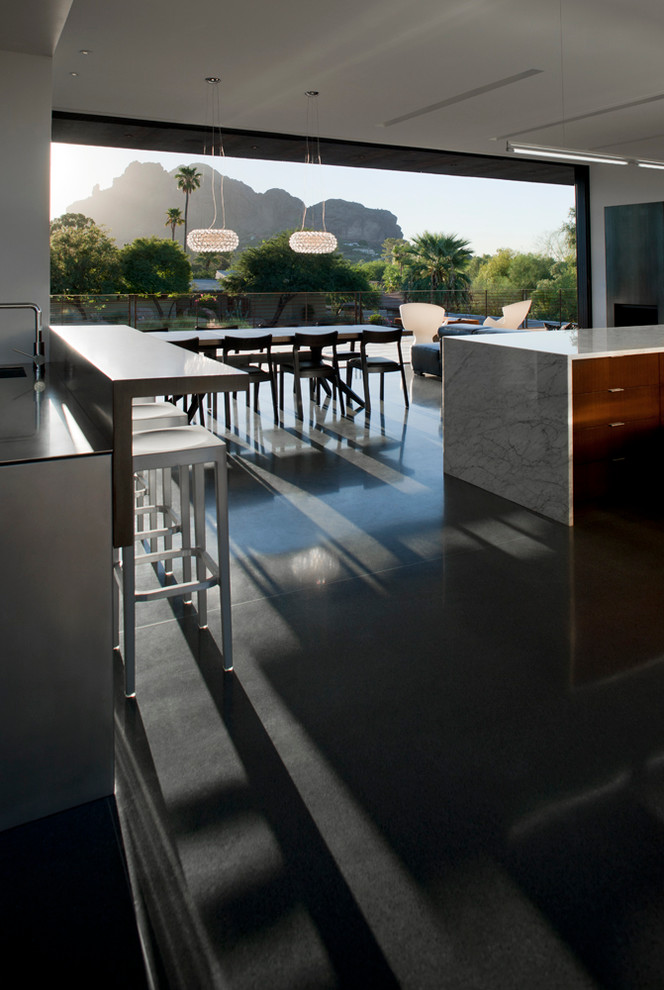 This is an example of a mid-sized modern u-shaped seated home bar in Phoenix with an undermount sink, flat-panel cabinets, grey cabinets, stainless steel benchtops and concrete floors.