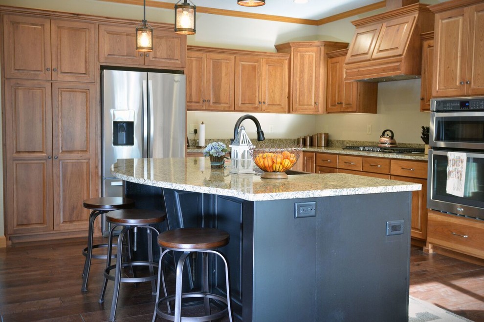 Large transitional l-shaped medium tone wood floor and brown floor kitchen photo with an island, a farmhouse sink, raised-panel cabinets, light wood cabinets, granite countertops and stainless steel appliances
