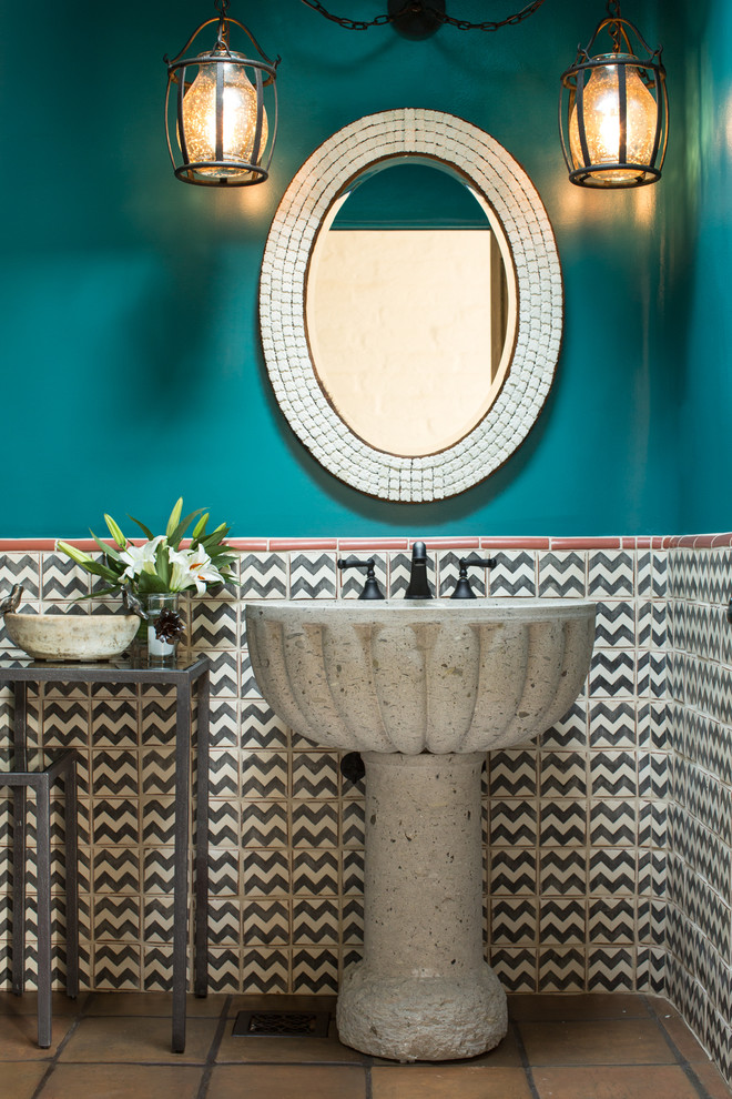 This is an example of a mid-sized powder room in Albuquerque with a pedestal sink, porcelain tile, blue walls, terra-cotta floors and multi-coloured tile.