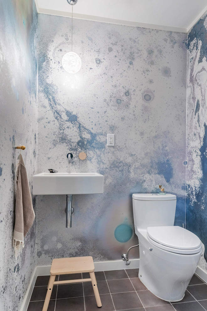 На фото: маленький туалет в стиле модернизм с унитазом-моноблоком, синими стенами, полом из керамогранита, подвесной раковиной, коричневым полом, подвесной тумбой и обоями на стенах для на участке и в саду с