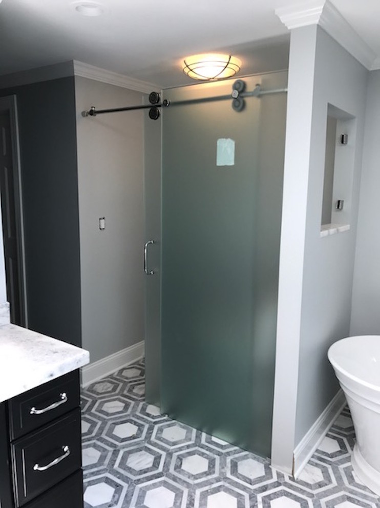 Design ideas for a mid-sized transitional master bathroom in New York with raised-panel cabinets, black cabinets, a corner shower, white tile, stone slab, grey walls, marble floors, an undermount sink, marble benchtops, multi-coloured floor and a hinged shower door.