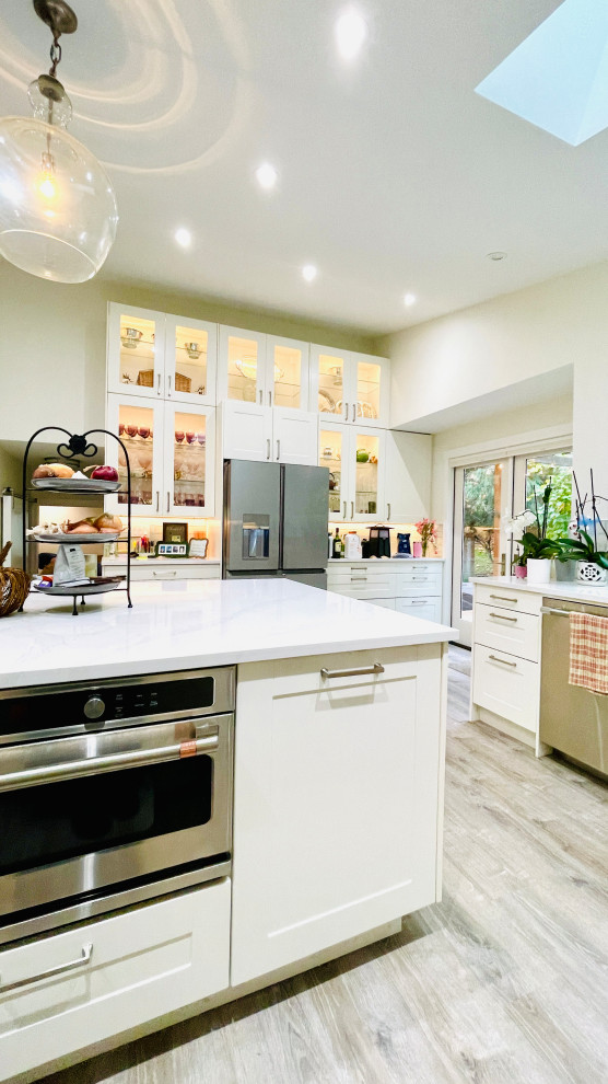 Inspiration for a large transitional u-shaped vinyl floor, gray floor and vaulted ceiling open concept kitchen remodel with a single-bowl sink, shaker cabinets, white cabinets, quartz countertops, glass tile backsplash, stainless steel appliances, an island and white countertops