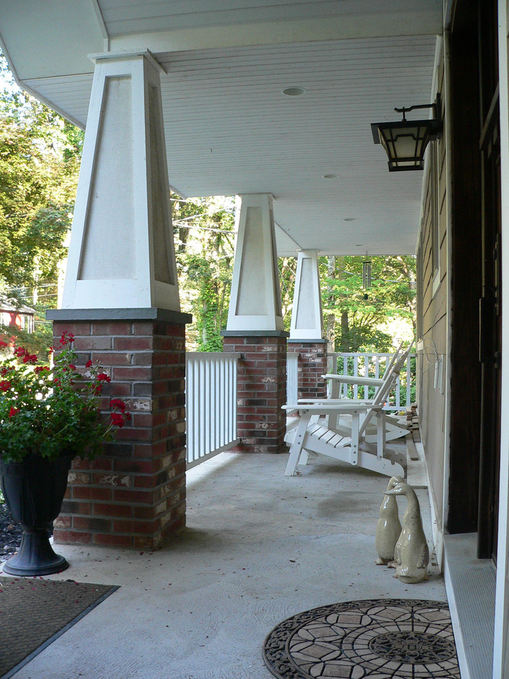 This is an example of a mid-sized arts and crafts front yard verandah in New York with concrete slab and a roof extension.