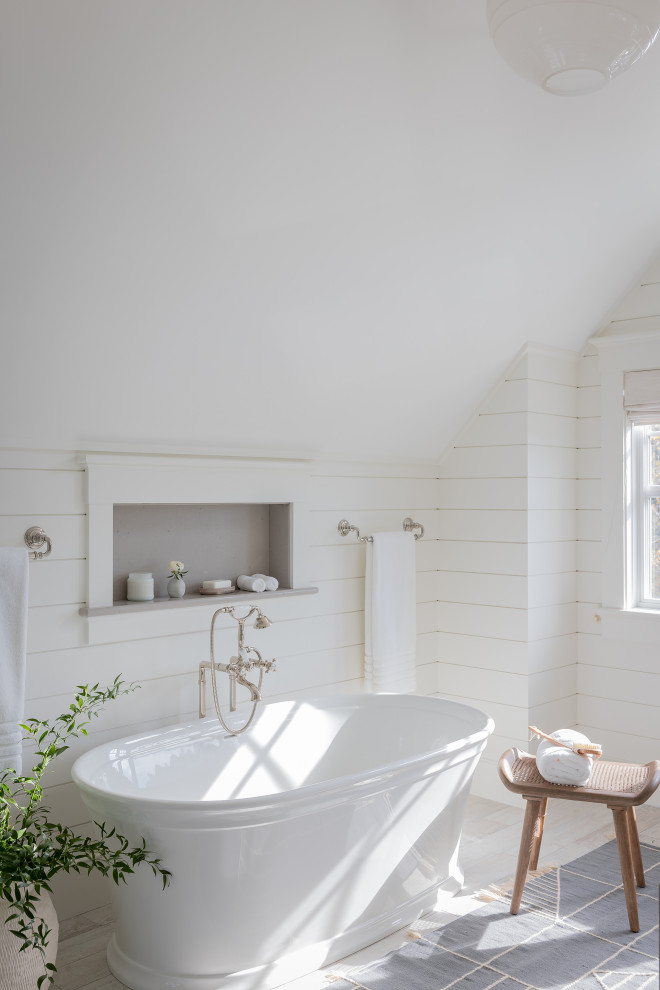 Photo of a beach style bathroom in Boston with a freestanding tub, white walls, light hardwood floors, grey floor, vaulted and planked wall panelling.