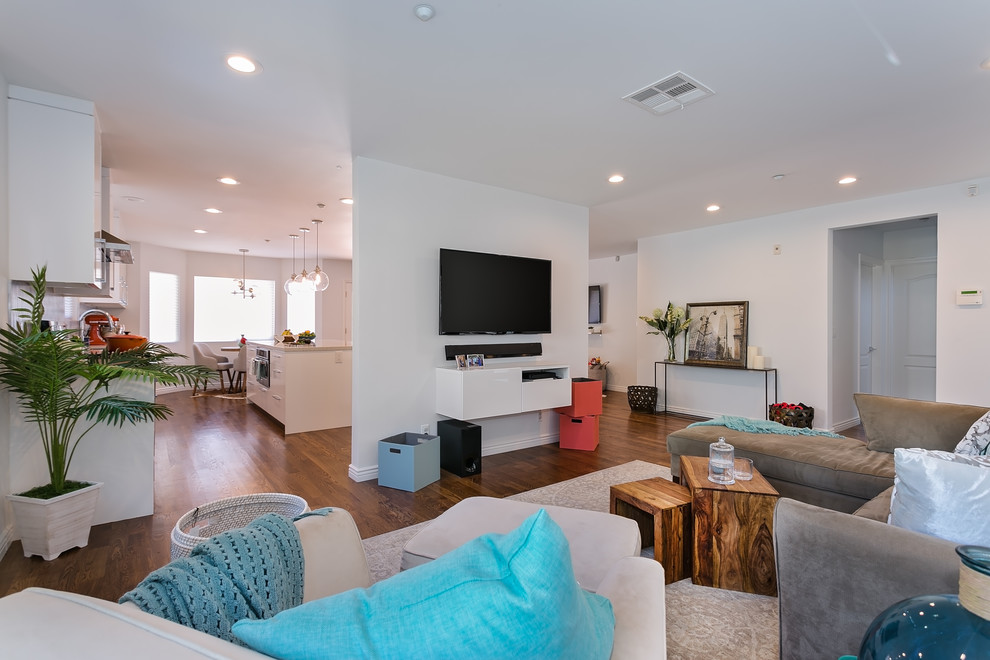 Mid-sized modern open concept living room in Los Angeles with grey walls, medium hardwood floors, no fireplace, a wall-mounted tv and brown floor.