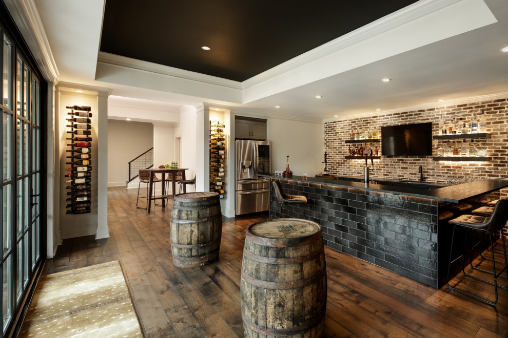 Photo of an industrial walk-out basement in Atlanta with a home bar, medium hardwood flooring, brown floors and brick walls.