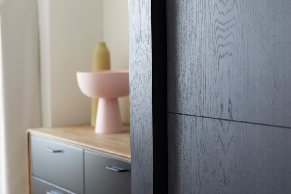 Medium sized modern master bedroom in London with beige walls and medium hardwood flooring.