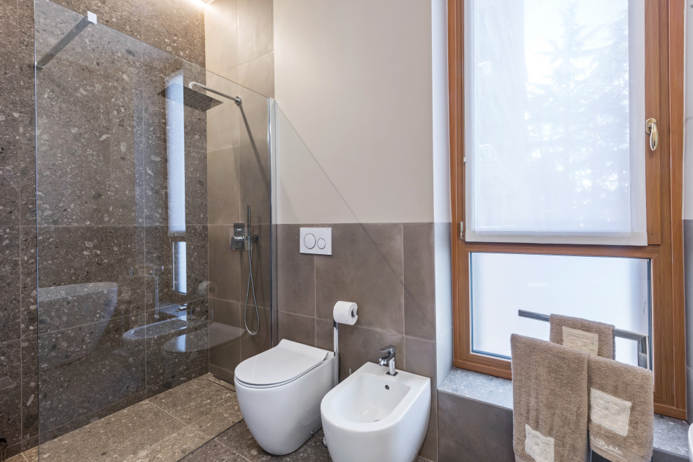 This is an example of a large contemporary 3/4 bathroom in Milan with beaded inset cabinets, light wood cabinets, a freestanding tub, a curbless shower, a two-piece toilet, gray tile, stone tile, white walls, porcelain floors, a vessel sink, limestone benchtops, grey floor, an open shower, grey benchtops, a double vanity, a floating vanity and recessed.