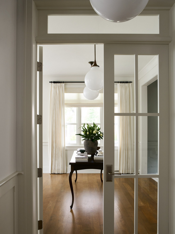 Inspiration for a mid-sized transitional light wood floor, brown floor and wainscoting hallway remodel in Chicago with white walls