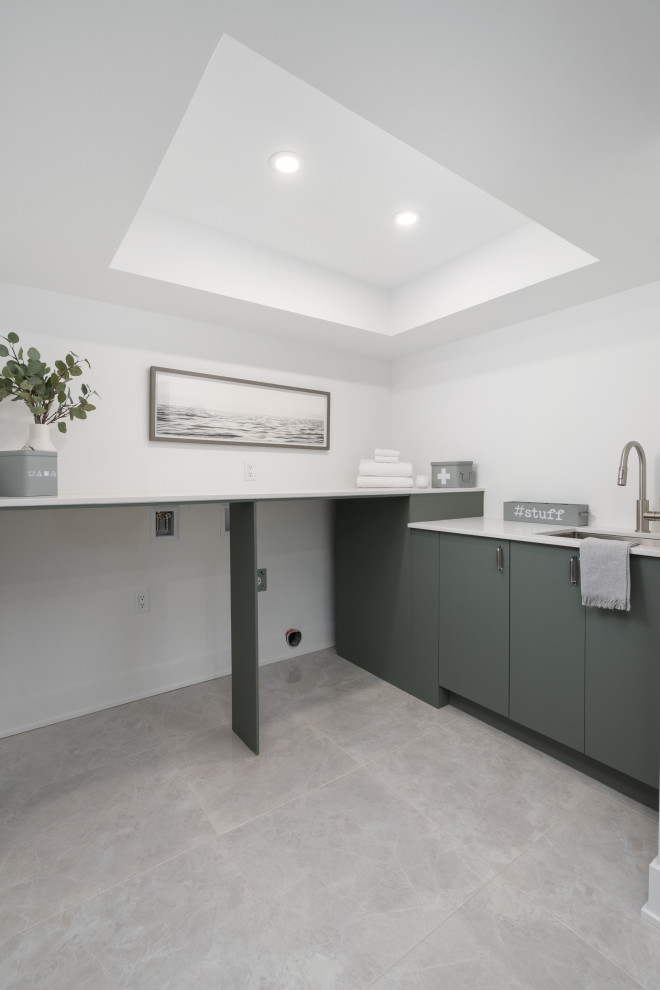 Inspiration for a large modern utility room in Montreal with an undermount sink, flat-panel cabinets, green cabinets, quartzite benchtops, white walls, ceramic floors, a side-by-side washer and dryer, grey floor, white benchtop and recessed.