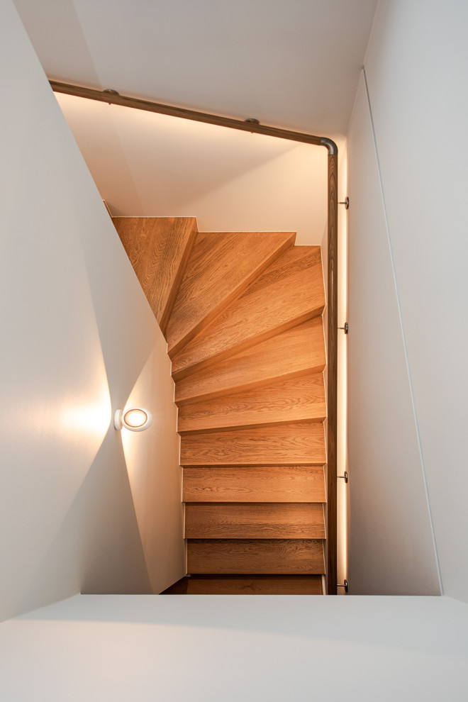 This is an example of a large contemporary wood curved wood railing staircase with wood risers.