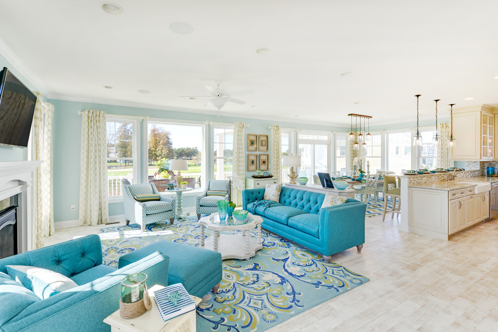 This is an example of a beach style open concept living room in Philadelphia with blue walls, light hardwood floors, a standard fireplace and a wall-mounted tv.