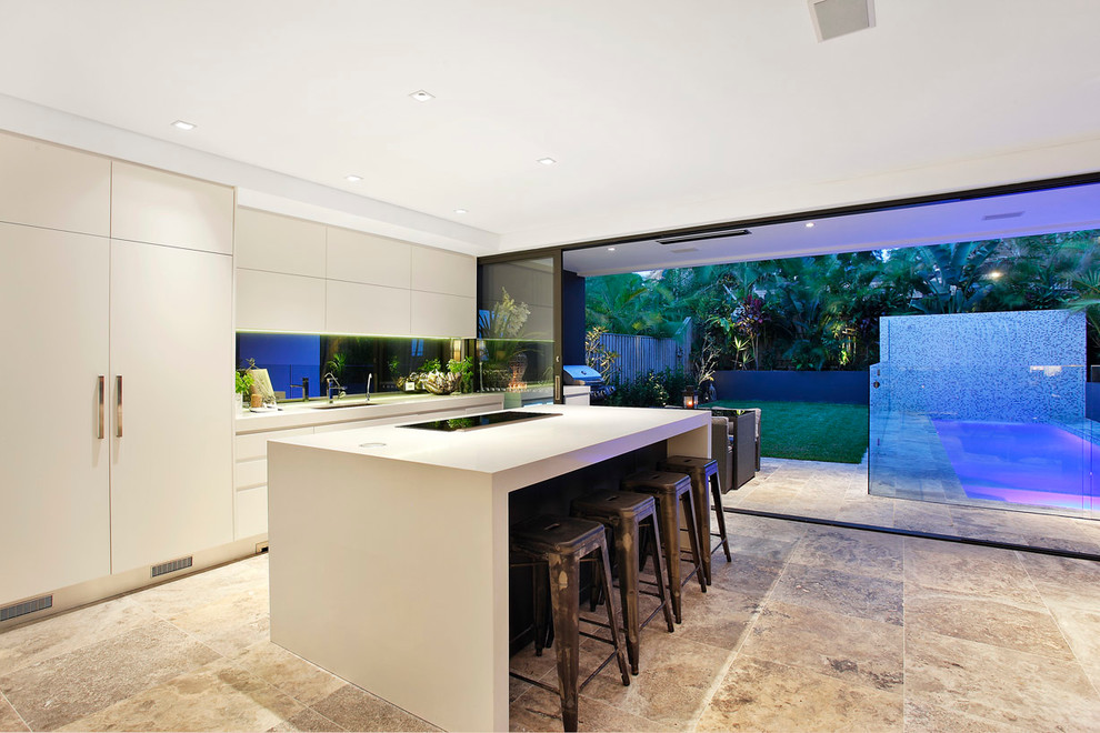 This is an example of a large contemporary galley open plan kitchen in Sydney with an undermount sink, flat-panel cabinets, white cabinets, quartz benchtops, metallic splashback, mirror splashback and stainless steel appliances.