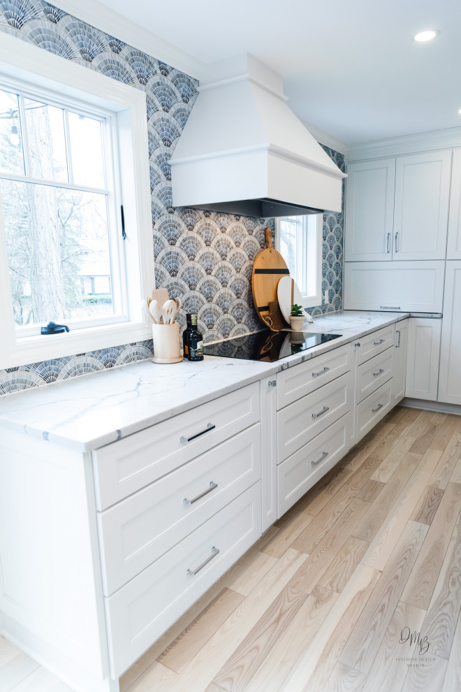 Transitional light wood floor and white floor kitchen photo with a farmhouse sink, flat-panel cabinets, blue cabinets, quartz countertops, blue backsplash, glass tile backsplash, stainless steel appliances, an island and white countertops