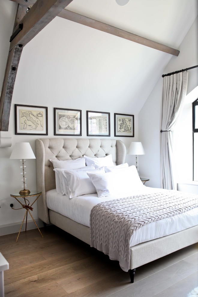 This is an example of a transitional bedroom in London with white walls, medium hardwood floors and no fireplace.