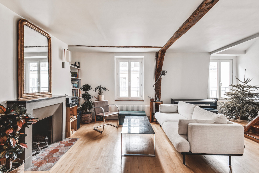 Photo of a mid-sized contemporary open concept living room in Paris with a library, white walls, light hardwood floors, a standard fireplace, a stone fireplace surround, no tv, brown floor, exposed beam and wood walls.