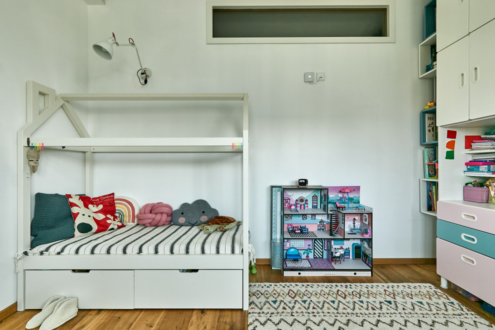 Modern inredning av ett litet flickrum kombinerat med sovrum och för 4-10-åringar, med vita väggar och mellanmörkt trägolv