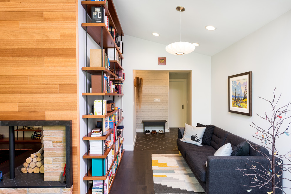 Small midcentury home office in Detroit with white walls, dark hardwood floors, a standard fireplace, a brick fireplace surround, brown floor and a library.