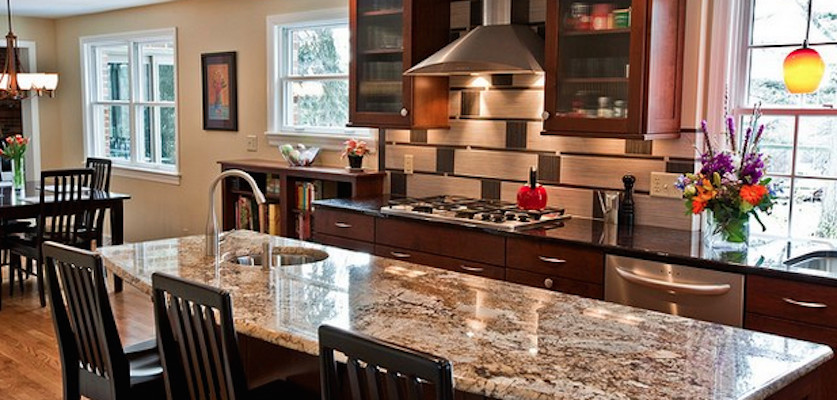 Example of a light wood floor eat-in kitchen design with a drop-in sink, flat-panel cabinets, dark wood cabinets, granite countertops, stainless steel appliances and an island