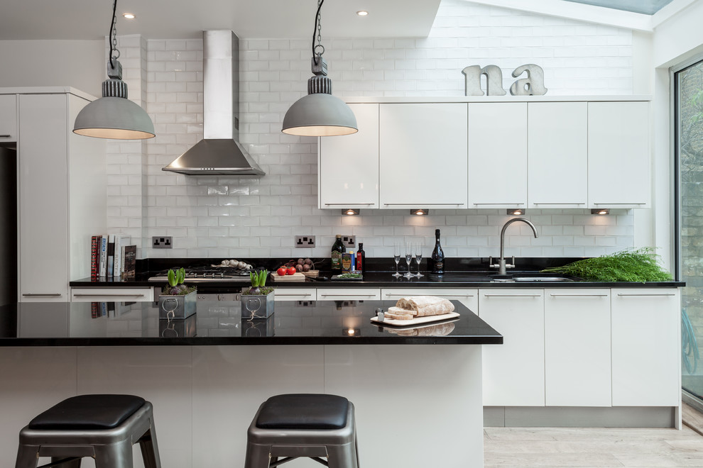 Design ideas for a contemporary kitchen in London with white cabinets, with island, an undermount sink, flat-panel cabinets, white splashback and subway tile splashback.