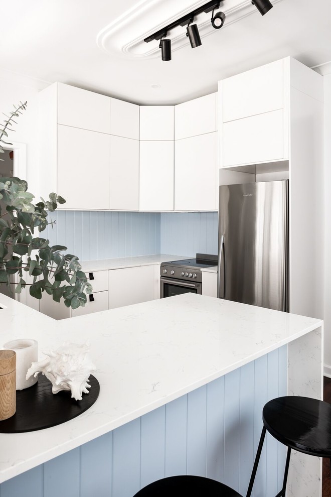 Small contemporary l-shaped kitchen pantry in Perth with white cabinets, quartz benchtops, blue splashback, timber splashback, stainless steel appliances, dark hardwood floors, brown floor and white benchtop.