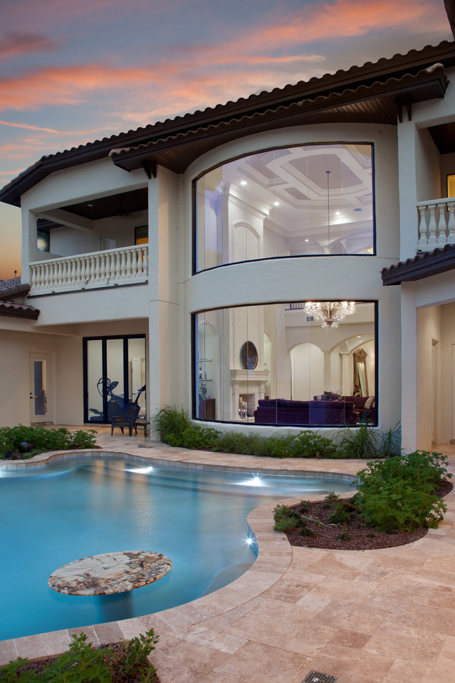 Photo of a large mediterranean backyard custom-shaped natural pool in Orlando with natural stone pavers.