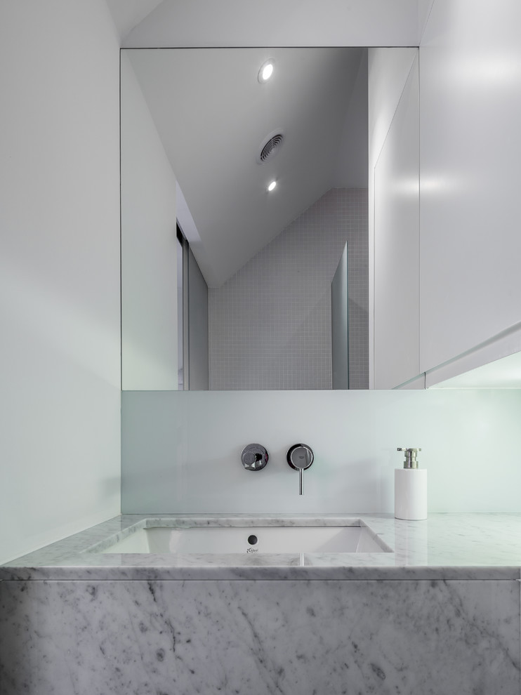 This is an example of a small modern bathroom in London with an undermount sink and marble benchtops.