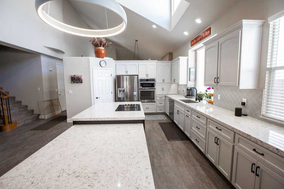 Photo of a large modern l-shaped eat-in kitchen in Sacramento with an undermount sink, white cabinets, quartzite benchtops, grey splashback, mosaic tile splashback, stainless steel appliances, with island and grey benchtop.