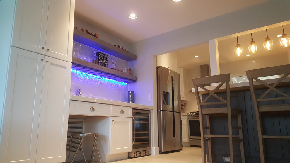 Example of a mid-sized transitional galley travertine floor and beige floor eat-in kitchen design in Miami with shaker cabinets, white cabinets, solid surface countertops, white backsplash, porcelain backsplash, stainless steel appliances, a farmhouse sink and a peninsula