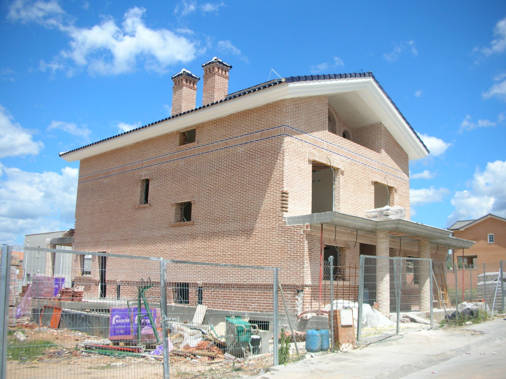 Expansive mediterranean brick red house exterior in Other with four or more storeys, a gable roof and a tile roof.