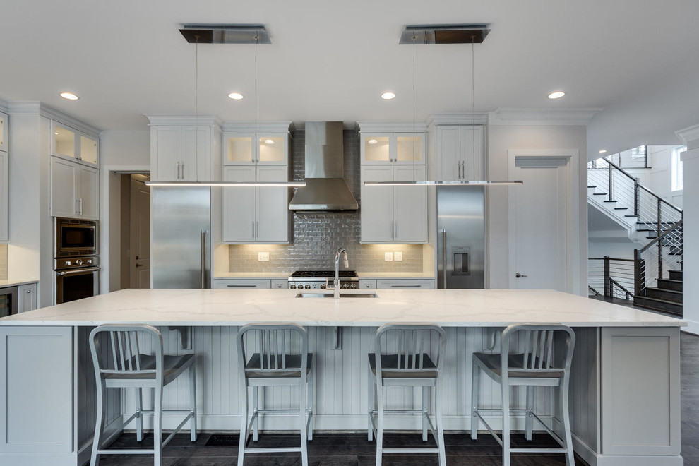 Large transitional l-shaped medium tone wood floor open concept kitchen photo in DC Metro with an undermount sink, shaker cabinets, white cabinets, quartz countertops, gray backsplash, glass tile backsplash, stainless steel appliances and an island