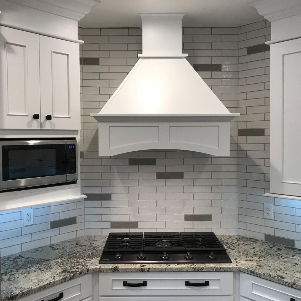 Inspiration for a mid-sized transitional u-shaped open plan kitchen in Denver with an undermount sink, shaker cabinets, white cabinets, granite benchtops, white splashback, subway tile splashback, stainless steel appliances, medium hardwood floors, with island and white benchtop.