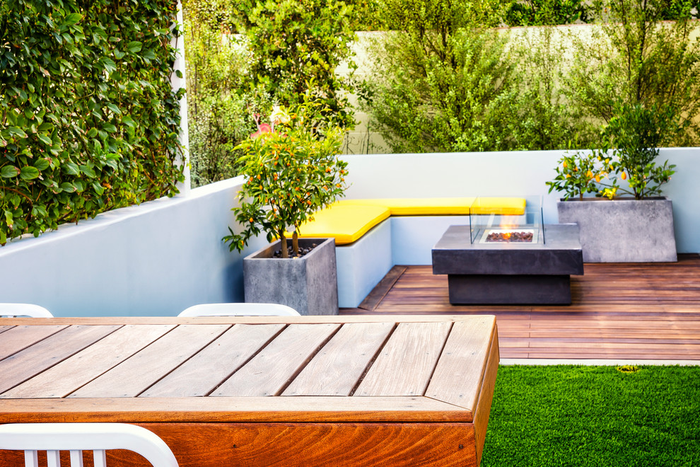 This is an example of a mid-sized modern backyard deck in Orange County with a fire feature.