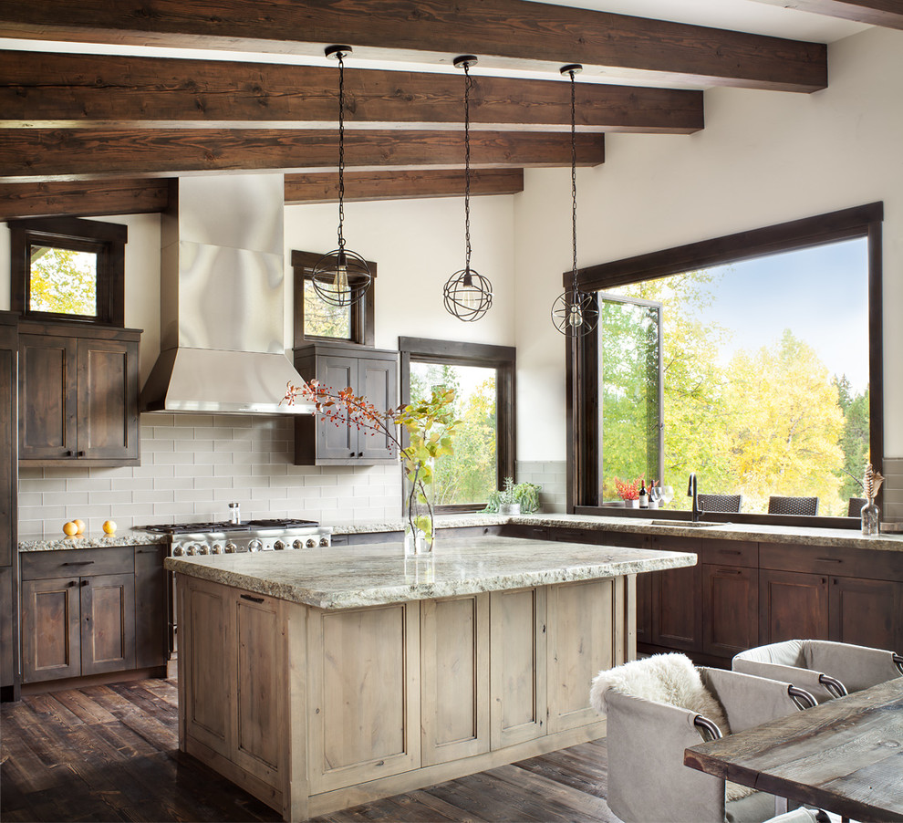 Example of a mountain style l-shaped dark wood floor eat-in kitchen design with shaker cabinets, dark wood cabinets, gray backsplash, stainless steel appliances and an island