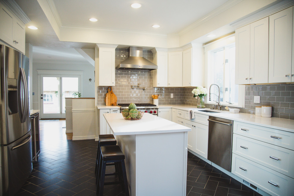 Photo of a mid-sized transitional u-shaped separate kitchen in Denver with an undermount sink, shaker cabinets, white cabinets, quartz benchtops, beige splashback, subway tile splashback, stainless steel appliances, porcelain floors and with island.