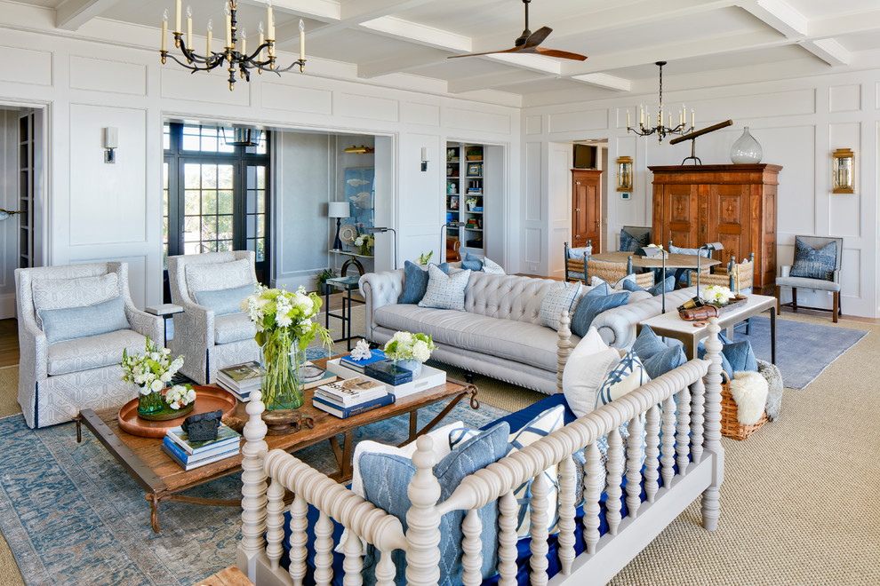 This is an example of a large beach style living room in Charleston with white walls, medium hardwood floors, a stone fireplace surround and a library.