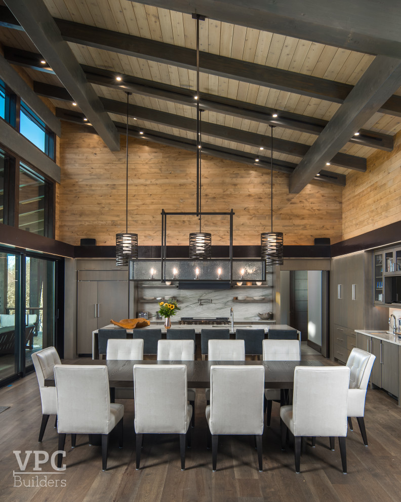 Cette image montre une très grande salle à manger ouverte sur la cuisine en bois avec un mur marron, un sol en bois brun et un plafond en bois.