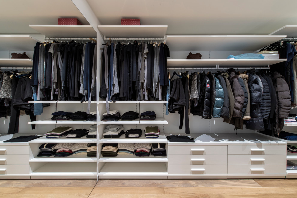 This is an example of a mid-sized contemporary gender-neutral walk-in wardrobe in Milan with open cabinets, white cabinets and light hardwood floors.