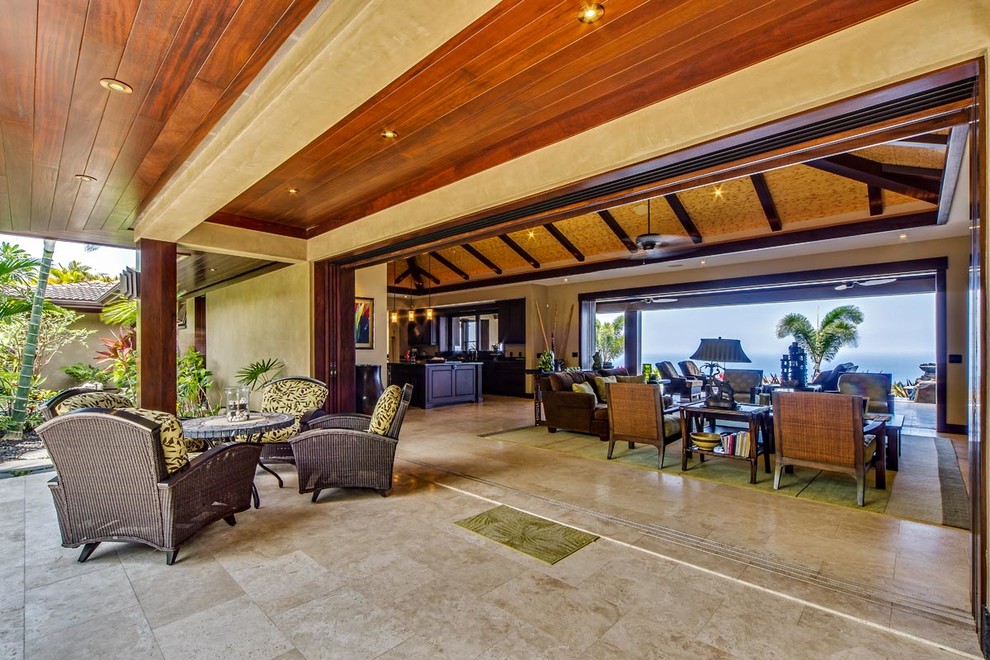Expansive tropical open concept family room in Hawaii with beige walls, travertine floors and no fireplace.