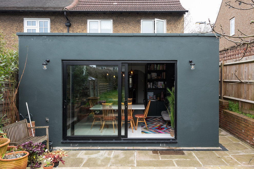 This is an example of a mid-sized eclectic one-storey concrete green house exterior in London with a flat roof and a green roof.