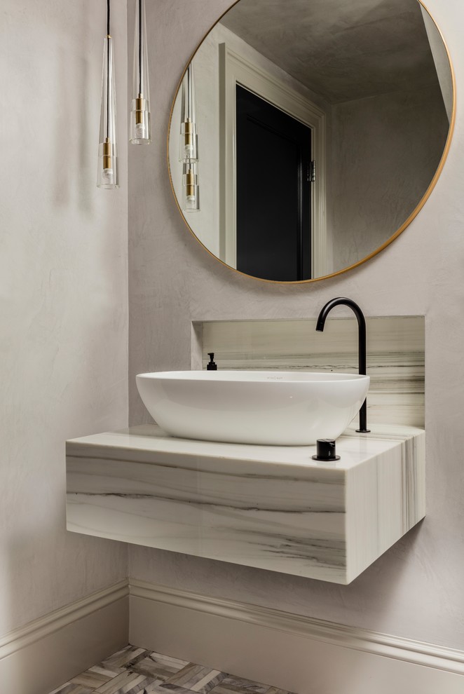 Photo of a small transitional powder room in Boston with open cabinets, a one-piece toilet, grey walls, mosaic tile floors, a vessel sink, marble benchtops and grey floor.