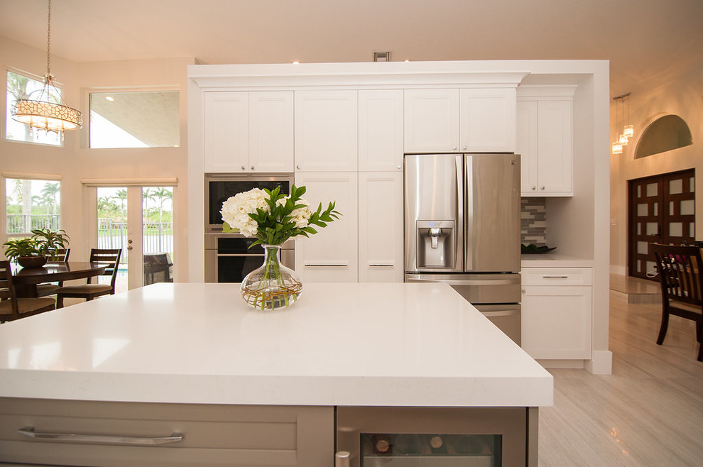Mid-sized transitional u-shaped eat-in kitchen photo in Miami with shaker cabinets, white cabinets, quartz countertops, gray backsplash, an island and white countertops