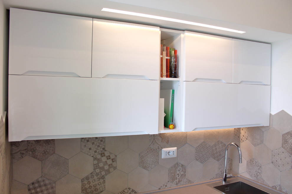 This is an example of a small contemporary galley eat-in kitchen in Bari with an integrated sink, beaded inset cabinets, white cabinets, laminate benchtops, multi-coloured splashback, porcelain splashback, stainless steel appliances, porcelain floors, no island and multi-coloured floor.