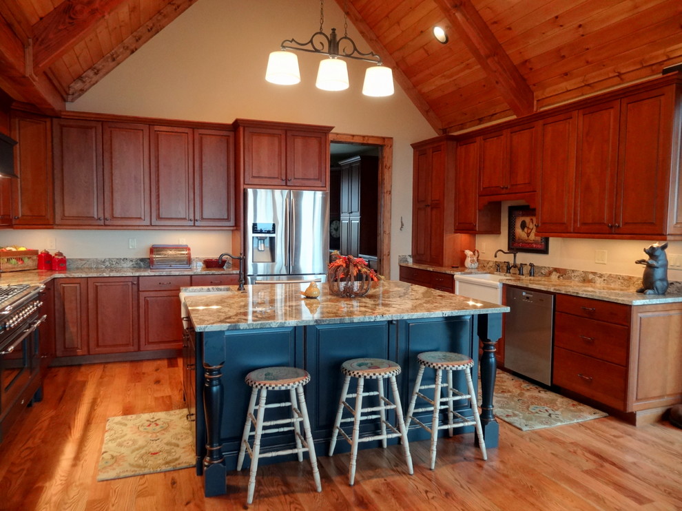 Example of a large mountain style u-shaped light wood floor eat-in kitchen design in Charlotte with a farmhouse sink, raised-panel cabinets, dark wood cabinets, granite countertops, beige backsplash, stainless steel appliances and an island